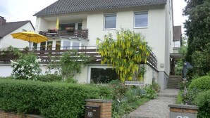Un immeuble résidentiel de deux étages doté d’un balcon, d’un parasol jaune et d’une enseigne indiquant qu’il s’agit d’un « appartement de vacances ».