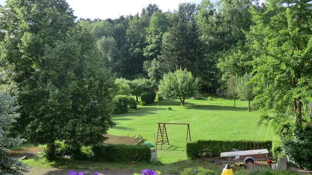 Un jardin bien entretenu, avec une pelouse, une balançoire et un petit abri de jardin.