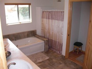 Een bad/douchecombinatie, een bubbelbad, een haardroger, handdoeken