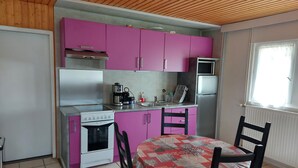 A compact kitchen with pink cabinets, a white stove, a microwave, and a sink. - Les Rousses-Bois d'avont (Bois-D'amont)