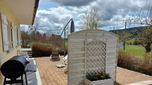 A patio with a grill, outdoor furniture, and a small garden area with flowers. - Les Rousses-Bois d'avont (Bois-D'amont)