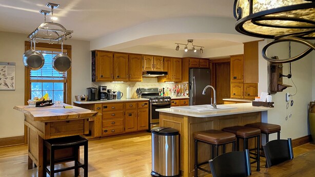 Une cuisine moderne avec des meubles en bois, des appareils en acier inoxydable et un îlot central doté de tabourets.