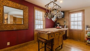 Une cuisine avec un îlot central en bois, un grand miroir décoratif et un porte-ustensiles.