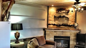 Un salon chaleureux avec une cheminée en pierre, un plafond en bois et un canapé confortable.