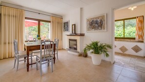 Een eetgedeelte met een tafel, stoelen, een open haard en een potplant.