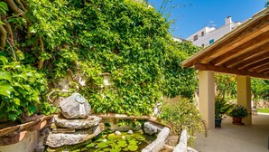 Een tuin met een vijver, rotsen en een pergola.