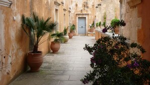 Un corredor arqueado con plantas en macetas y una puerta al final.