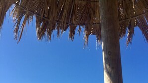 Escena de playa con una estructura de techo de paja y una pila de piedras.