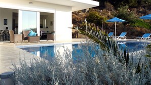 Un área de piscina moderna con sillones de descanso y zona de comedor.