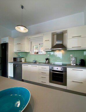 Prepare meals with ease in this kitchen, featuring a stainless steel refrigerator, microwave, and coffee maker.