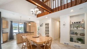 A spacious kitchen with a wooden dining table and chairs, a built-in island, and a view to the outdoors.