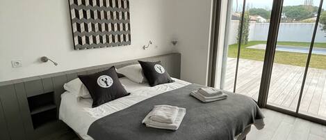 A modern bedroom with a large bed, a view of the outdoors, and a unique wall art piece.