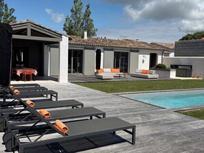 A modern outdoor pool area with lounge chairs and a dining setup.