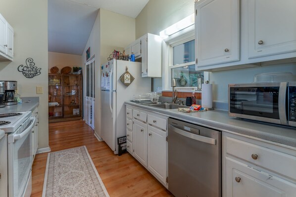 A kitchen with white cabinets, a stainless steel refrigerator, a microwave, and a dishwasher.
