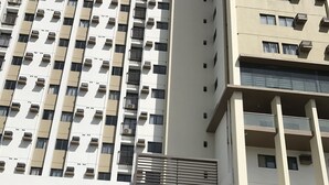 A multi-story building with a modern design, featuring balconies and a prominent entrance with steps. - Clean and cozy apartment (Cebu City)
