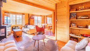 Een gezellig blokhutinterieur met een woonkamer, eethoek en een open haard.