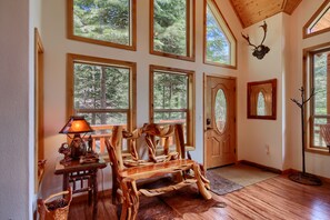 A spacious room with large windows, wooden furniture, and a ceiling with exposed beams.