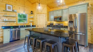 Una cocina moderna con paredes de madera, electrodomésticos de acero inoxidable y una isla central con taburetes de bar.