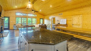 Una cabaña de madera espaciosa con una isla grande en la cocina, un comedor y una zona de estar acogedora con chimenea.