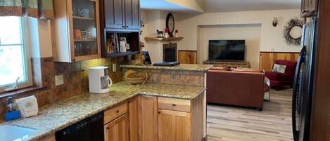 A kitchen with wooden cabinets, granite countertops, a dishwasher, and a ceiling fan.