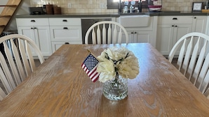 A dining table with a vase of flowers and an American flag, surrounded by white chairs. - 9 AM check in/9 PM check out, Custom Built, no shared walls free standing home (Redmond)