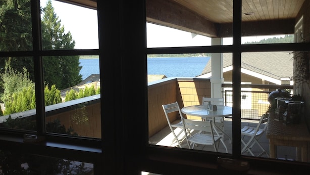 A balcony with a view of the sea, a table, and chairs. - 9 AM check in/9 PM check out, Custom Built, no shared walls free standing home (Redmond)