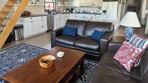 A modern living room with a brown leather sofa, a wooden coffee table, and a patterned rug. - 9 AM check in/9 PM check out, Custom Built, no shared walls free standing home (Redmond)