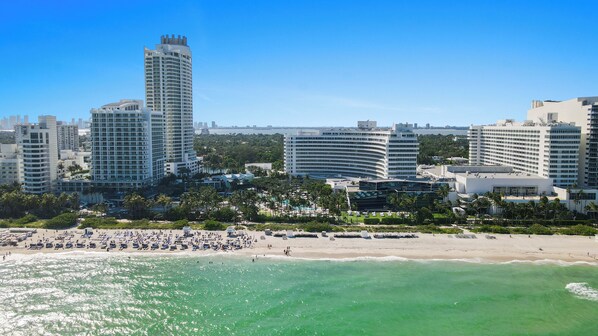 A coastal cityscape with high-rise buildings, a beach, and a clear blue sky.