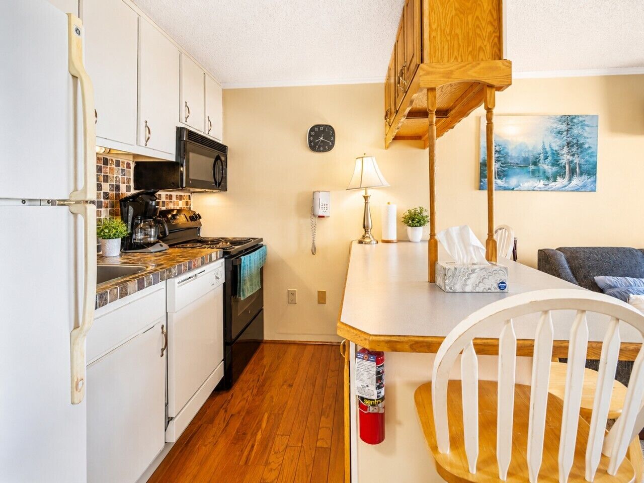 A compact kitchen with white cabinets, a microwave, a stove, and a dining area with a table and chairs.