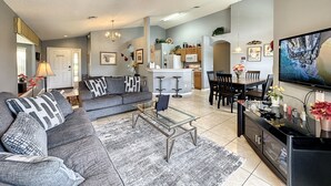A spacious living room with a gray sofa, a coffee table, and a TV. - Resort Community - Waterfront Home Next Door to Disney!  (Kissimmee)