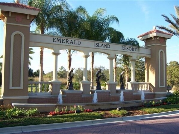 A sign for Emerald Island Resort with classical columns and statues.