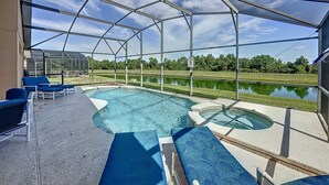 A covered outdoor swimming pool with blue lounge chairs and a view of a lake. - Resort Community - Waterfront Home Next Door to Disney!  (Kissimmee)