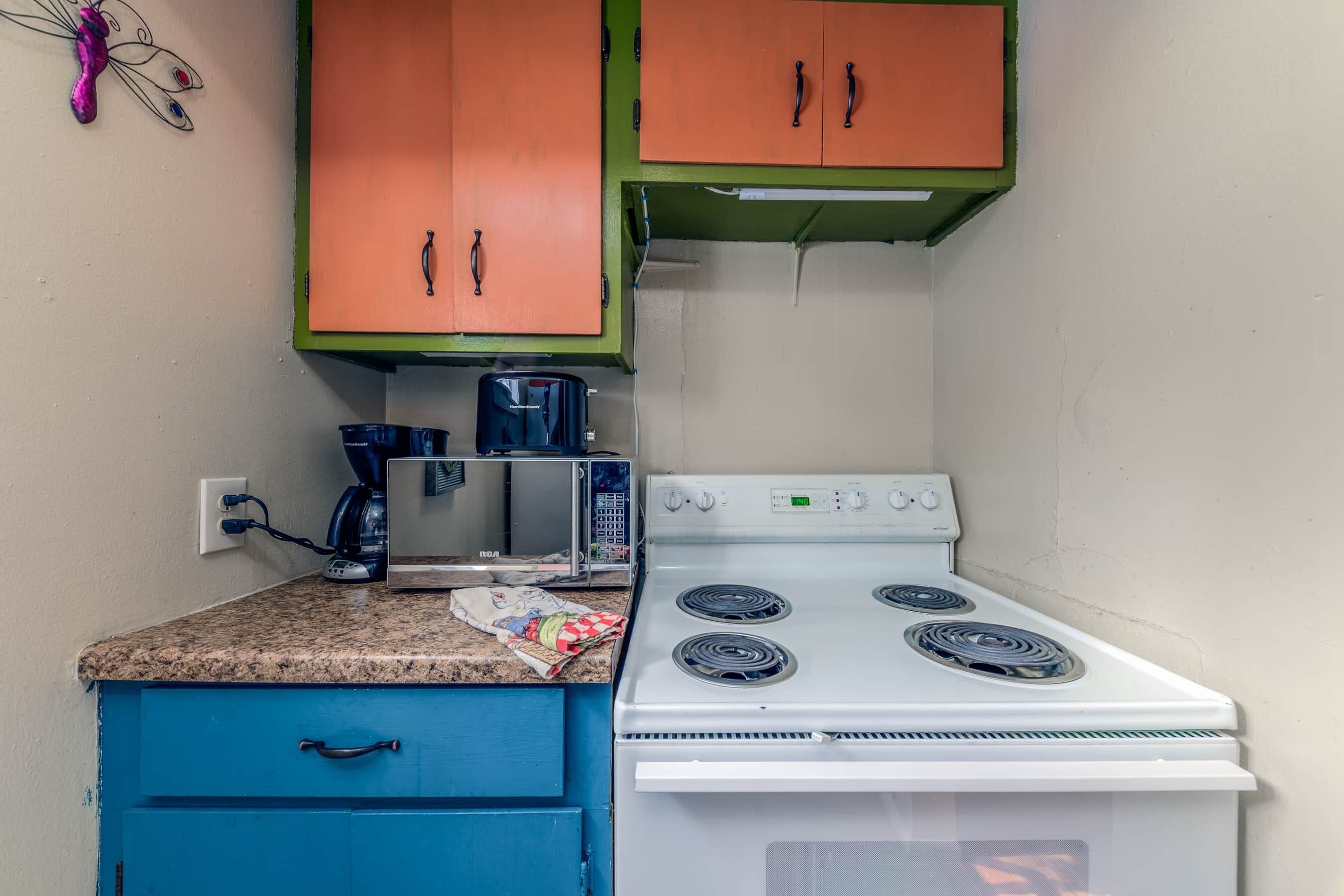 Une cuisine avec un four blanc, des placards bleus et un four à micro-ondes.