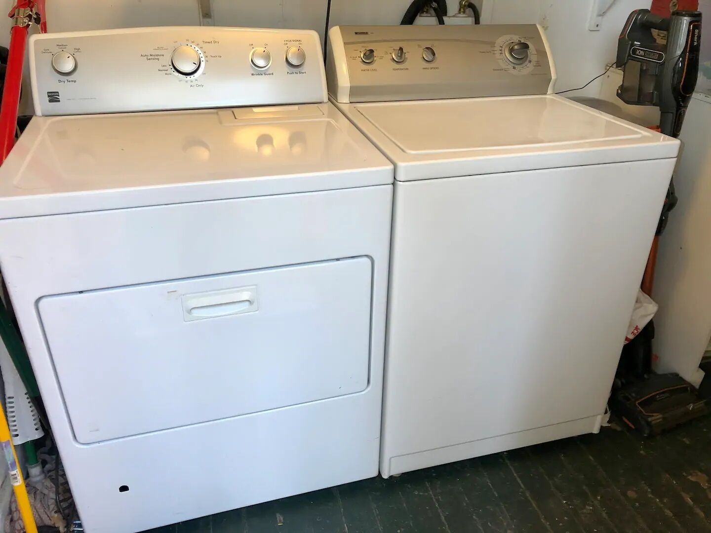 A white stacked washer and dryer unit with control knobs and a front door.