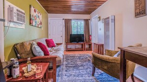 A cozy living room with a wooden ceiling, a television on a stand, a sofa with cushions, a dining table, and a patterned rug. - RECHARGE,  Pets Welcome,  Fast Wifi,  Opt HOT TUB (Ruidoso)