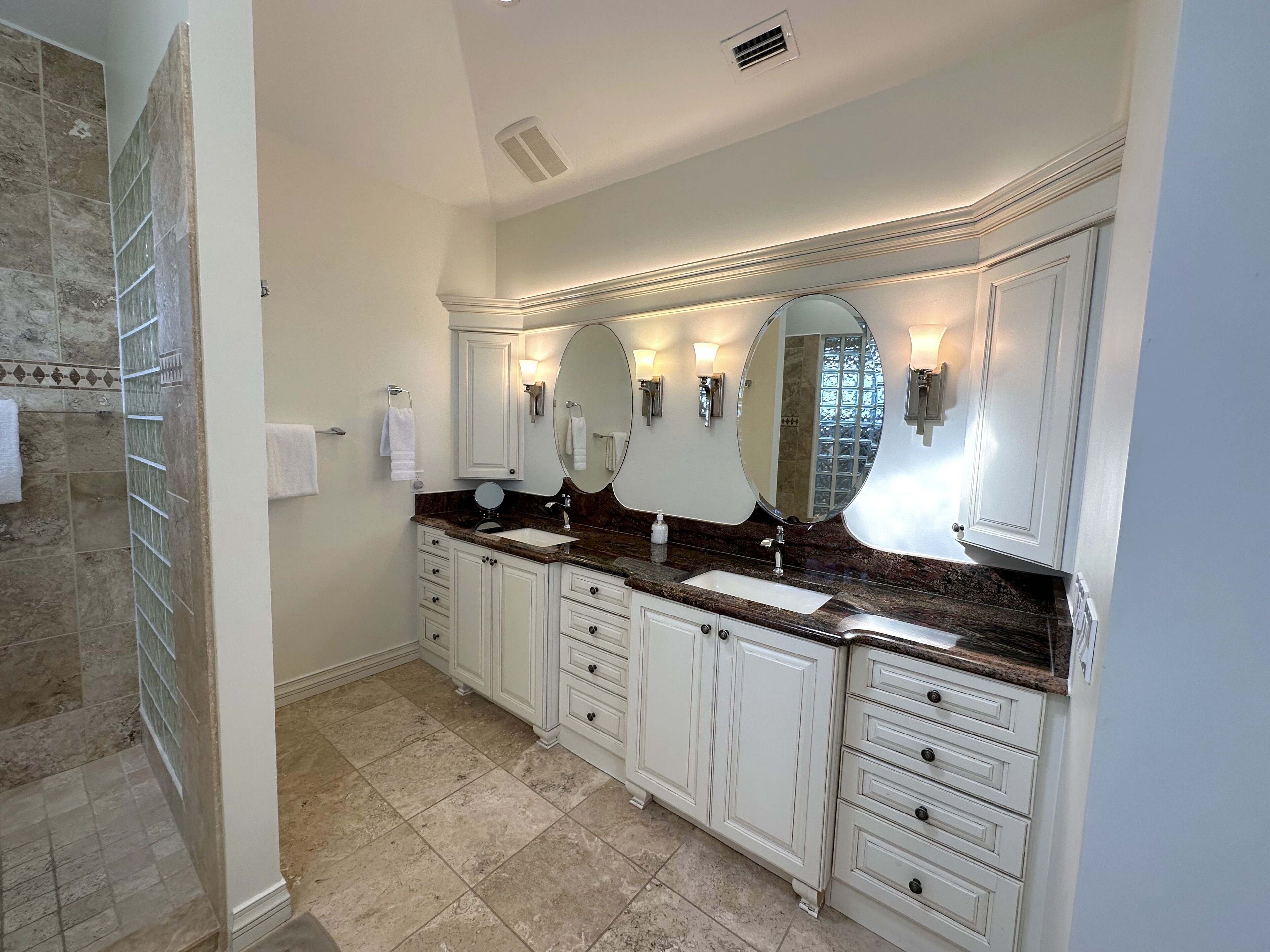 Une salle de bain spacieuse dotée d’un grand meuble-lavabo, de deux vasques et d’une douche à l’italienne.