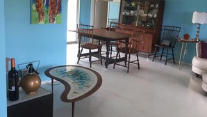 A dining area with a wooden table and chairs, a cabinet with glass doors, and a painting on the wall. - Beautiful 1800 square foot Mid Century Home  (Venice)