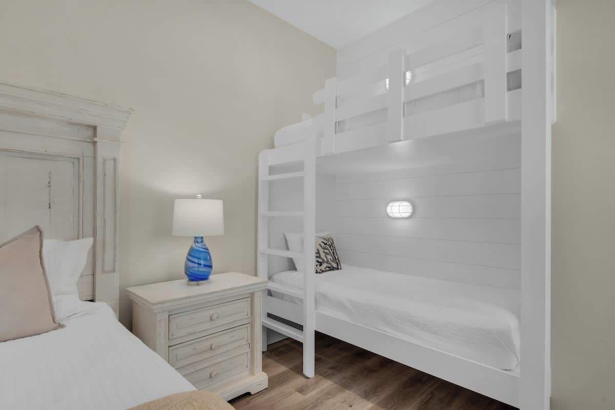 A bunk bed room with a white dresser and a lamp.