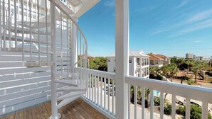 A balcony with a white railing, a wooden floor, and a view of neighboring houses and trees. - Good Day Sunshine | 100 Steps to Beach | 8 Free Beach Chairs through October! | Huge Private Pool & Lush Backyard (Miramar Beach)