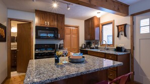 A kitchen with granite countertops, wooden cabinets, a microwave, stove, and a coffee maker. - Beautifully Furnished, Clean, Cozy Cabin Next to Rocky! Walk to RMNP & YMCA (Estes Park)