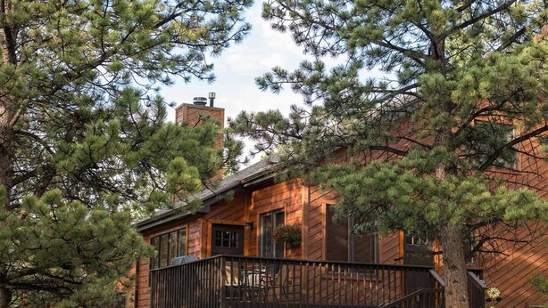 A rustic cabin with a wooden exterior, a deck, and a chimney. - Beautifully Furnished, Clean, Cozy Cabin Next to Rocky! Walk to RMNP & YMCA (Estes Park)