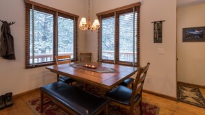 A dining area with a wooden table, benches, and a chandelier. - Beautifully Furnished, Clean, Cozy Cabin Next to Rocky! Walk to RMNP & YMCA (Estes Park)