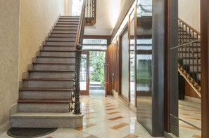 A grand staircase with a polished stone floor and wooden handrails.