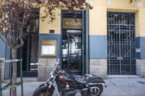 A motorcycle parked in front of a building with a sign that reads "VI COOL".