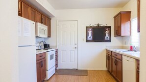 A compact kitchen with wooden cabinets, a white refrigerator, a microwave, an oven, and a sink. - Stay at Roosevelt Row / Modern 2BR 2BA Condo (Phoenix)