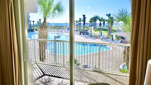 A balcony with a view of a pool and palm trees. - Destin West Gulfside #214 ~Free Beach Service! ~Multiple Pools & Lazy River! (Fort Walton Beach)