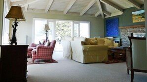 A spacious living room with a high ceiling, a sofa, a chair, and a lamp. - Ocean View Retreat in Carmel Meadows w/ Hot Tub. Walk to Trails & Beach! (Carmel)