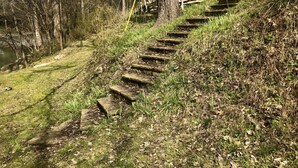 A set of stone steps leading up a grassy slope, surrounded by trees and a wooden fence. - Pet Friendly ☀River Access☀2 bdrm/1 bath☀At Park Entrance☀Screened Porch (Townsend)