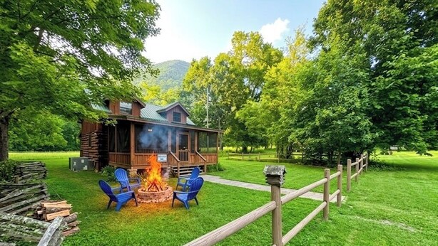 A rustic cabin with a fire pit and blue chairs, surrounded by a wooden fence and lush greenery. - Pet Friendly ☀River Access☀2 bdrm/1 bath☀At Park Entrance☀Screened Porch (Townsend)