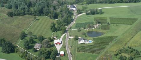 Vue aérienne d’une propriété rurale avec des champs, un étang et une ferme.